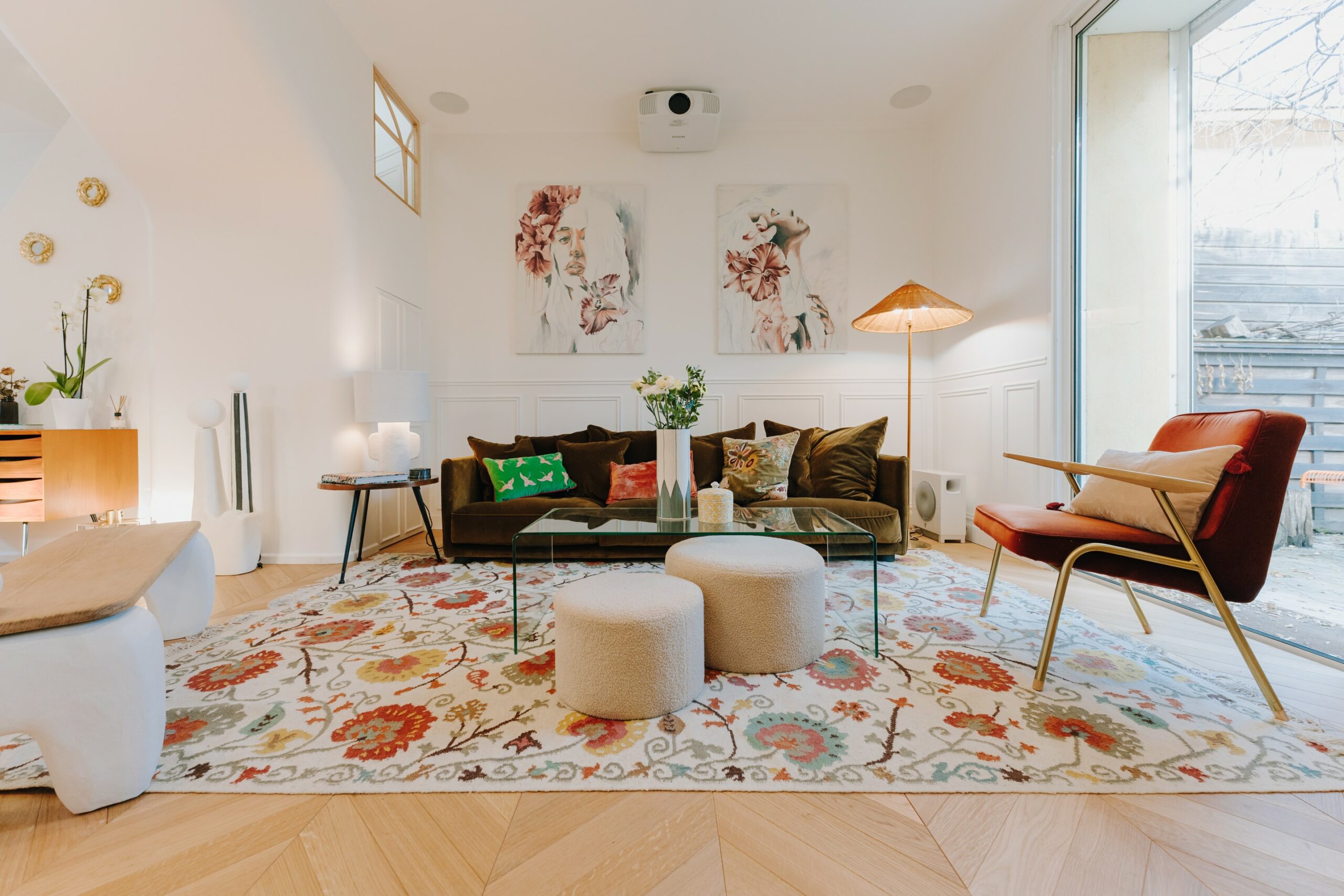 le salon est baigné de lumière naturelle grâce à de grandes fenêtres et une porte vitrée donnant sur l'extérieur. Les murs blancs et le parquet en point de Hongrie contribuent à créer une atmosphère lumineuse et spacieuse.